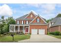Charming two-story brick home with a covered front porch, two-car garage, and landscaped yard at 1140 Promontory Drive, Marietta, GA 30062