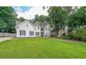 View of a two-story stucco home with manicured lawn and mature shade trees at 2970 Chardonnay Ln, Cumming, GA 30041