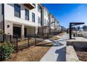 Street view of modern townhomes featuring brick accents, iron fencing, and manicured landscaping at 350 Olmstead Way # 29, Alpharetta, GA 30022
