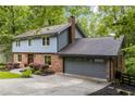 Exterior view of home, featuring brick facade, siding, attached garage, and mature trees at 2892 Guinevere Ne Dr, Atlanta, GA 30345