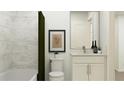 Cozy bathroom features a shower with green curtain, a toilet and vanity with a mirror and lighting at 811 Atkins Ln, Woodstock, GA 30188