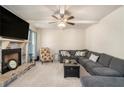 Cozy living room with a stone fireplace, plush seating, and a ceiling fan at 316 Sierra Ct, Mcdonough, GA 30253