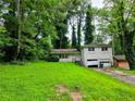Split-level home with brick facade, lush greenery, attached garage, and overgrown yard at 3429 Pheasant Ct, Decatur, GA 30034