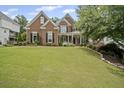 Charming two-story brick home with a well-manicured lawn, mature trees, and a welcoming front porch at 4320 Cody Ct, Cumming, GA 30040