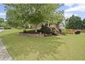 Beautifully landscaped yard with mature trees, stone retaining wall, and lush green lawn at 4320 Cody Ct, Cumming, GA 30040