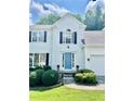 Traditional home featuring manicured shrubbery, a blue front door, and an attached two car garage at 405 Rosedown Way, Lawrenceville, GA 30043