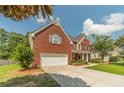 View of the home's exterior featuring a two-car garage, brick facade, and landscaped lawn at 2479 Mitford Ct, Dacula, GA 30019