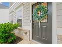 Close-up of a stylish gray front door adorned with a green wreath, set against a backdrop of brick and siding at 306 Coppergate Ct, Holly Springs, GA 30115