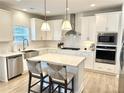 Bright kitchen features white cabinetry, stainless steel appliances, a central island with seating, and pendant lighting at 306 Coppergate Ct, Holly Springs, GA 30115