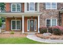 Charming front porch with stone accents, columns, and an elegant front door, surrounded by manicured landscaping at 5635 Upper Creek Ct, Suwanee, GA 30024