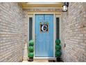 Charming light blue front door with decorative wreath and topiaries, set in a classic brick facade at 130 Stewart Hollow Ln, Covington, GA 30016