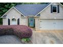 Close up of a brick home with a two car garage, lush landscaping and a pop of color from the front door at 130 Stewart Hollow Ln, Covington, GA 30016