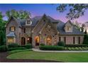 Charming brick home with manicured landscaping, arched entryway, and inviting exterior lighting at twilight at 4304 Berkford Ne Cir, Brookhaven, GA 30319