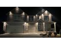 Beautiful two-story home with elegant exterior lighting illuminating the façade and yard at night at 157 Donovan Ave, Locust Grove, GA 30248