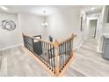 Bright upper hallway featuring laminate flooring, a modern chandelier, and stylish wood and iron railing at 6965 Kimberland Gardens Ln, Lithonia, GA 30058