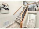 Stylish staircase with iron balusters, wooden handrail, and gray laminate flooring leading to the upper level at 6965 Kimberland Gardens Ln, Lithonia, GA 30058