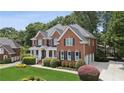 Traditional brick home featuring an attached garage and lush greenery at 2145 Sugarstone Ct, Lawrenceville, GA 30043