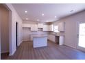 Bright kitchen featuring white cabinets, granite countertops, and an island with wood grain vinyl flooring at 324 Bloomfield Cir, Canton, GA 30114