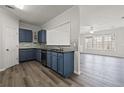 Modern kitchen featuring blue cabinets, stainless steel appliances, granite countertops and hardwood floors at 1510 Paramount Ln, Sugar Hill, GA 30518
