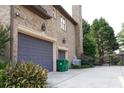 Attached two-car garage and brick exterior detailing, accompanied by lush landscaping at 4663 Mossey Dr, Lithonia, GA 30038