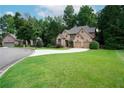 Beautiful home featuring lush green lawn, mature trees, and a circular driveway at 7185 Hartsfield Pl, Suwanee, GA 30024