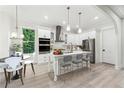 Bright kitchen with stainless steel appliances, white cabinetry, an island with seating, and modern pendant lighting at 7650 Abbey Glen Dr, Cumming, GA 30028