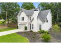 Aerial view of charming two-story home with an attached garage, manicured lawn, and fresh landscaping at 3040 Ivey Oaks Ln, Roswell, GA 30076