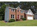 Inviting two-story brick house with light grey siding, a red door, well-kept lawn, and an attached two-car garage at 1471 Ashwood Way, Lawrenceville, GA 30043