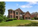Elegant two-story red brick home featuring a well-manicured lawn and attached two-car garage at 141 Ennisbrook Se Dr, Smyrna, GA 30082
