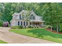Charming home featuring a covered front porch, beautiful lawn, and mature trees at 3871 Lake Juliette Dr, Buford, GA 30519