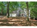 Charming two-story home with a gray exterior and a two-car garage nestled in a wooded lot at 545 Woodman Pl, Roswell, GA 30076