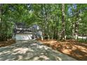 Charming two-story home with a gray exterior and a two-car garage and driveway nestled in a wooded lot at 545 Woodman Pl, Roswell, GA 30076
