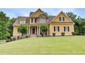 Charming two-story home featuring a well-manicured lawn, complemented by lush landscaping and a stone facade at 116 Archstone Sq, Mcdonough, GA 30253