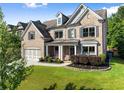 Beautiful two-story brick home featuring mature landscaping, an attached garage and an inviting front porch at 5157 Sunlake Dr, Hoschton, GA 30548
