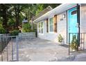 Close-up of the entrance with a charming stone patio, gray siding, cute shutters, and a blue front door at 3046 Dobbs Way, East Point, GA 30344