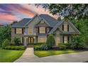 Charming two-story home illuminated by a sunset, featuring manicured landscaping, and a welcoming front entrance at 7615 Laurel Oak Dr, Suwanee, GA 30024