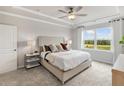 Bright bedroom with a plush upholstered bed, tray ceiling, and a large window showcasing scenic views at 710 Pineberry Ct, Grayson, GA 30017