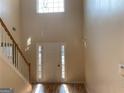 Bright, two-story foyer with hardwood floors, white front door and staircase at 7981 Gossamer Dr, Fairburn, GA 30213