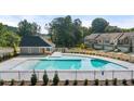 Community pool with sundeck and cabana surrounded by lush landscaping and townhomes at 1400 Gray Branch Dr, Lawrenceville, GA 30045