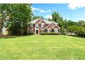 Beautiful red brick home showcasing a large green lawn and mature trees at 194 Lake Ruby Dr, Suwanee, GA 30024