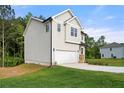 Side view of a two-story home with light siding, a two-car garage, and a green lawn at 4095 Oriole Ln, Fairburn, GA 30213