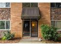 Apartment building entrance featuring a dark awning, stone and brick accents, and neat landscaping at 115 Biscayne Nw Dr # F10, Atlanta, GA 30309