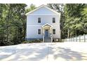 Charming three-story home boasts a welcoming entrance, blue door, and is set amongst lush trees at 2125 Clay Rd, Austell, GA 30106