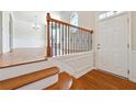 Bright foyer with hardwood floors, stairs with wood and iron railing, and white door at 6043 China Rose Lane, Johns Creek, GA 30097