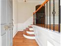 Inviting foyer featuring hardwood floors, white wainscoting, and stairs with wrought iron railing at 6043 China Rose Lane, Johns Creek, GA 30097