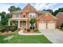 Beautiful two-story brick home featuring a covered front porch and a two-car garage at 1680 Laleiah Dr, Cumming, GA 30041