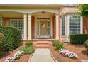 Charming front porch with decorative columns and flower beds leading to the front door at 1680 Laleiah Dr, Cumming, GA 30041
