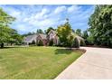 Landscaped lawn and paved driveway leading to a charming home with mature trees at 3885 Lake Juliette Dr, Buford, GA 30519