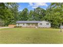Beautifully landscaped front yard with mature trees, well-maintained lawn, and a welcoming facade with a covered porch at 6142 Hutchins Dr, Buford, GA 30518