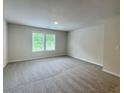 Bright, carpeted bedroom featuring a large window and neutral wall color at 596 Rodeo Dr, Auburn, GA 30011